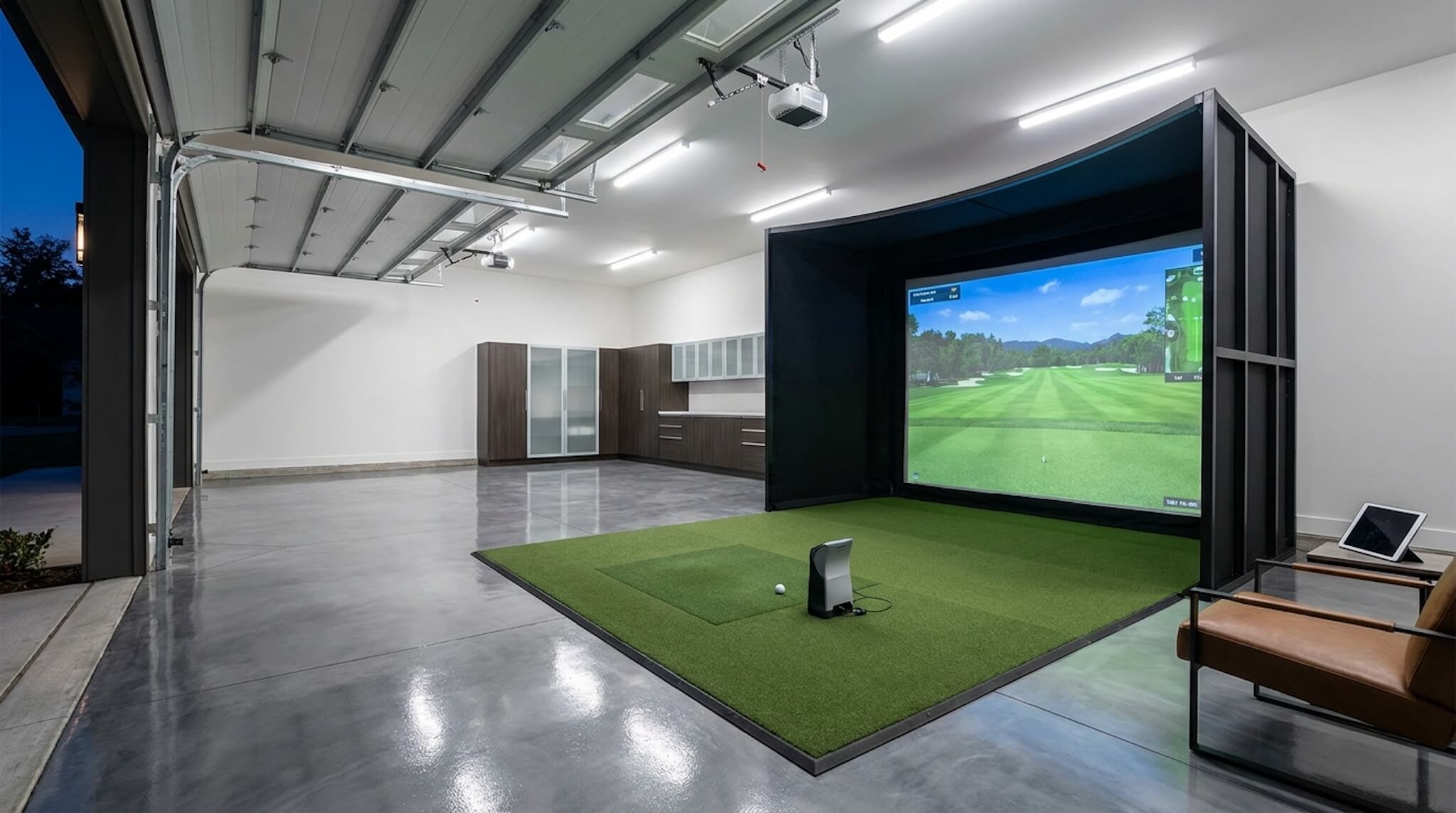 The Premium Garage Golf Simulator Package installed in a modern home garage, featuring a large impact screen and hitting mat.